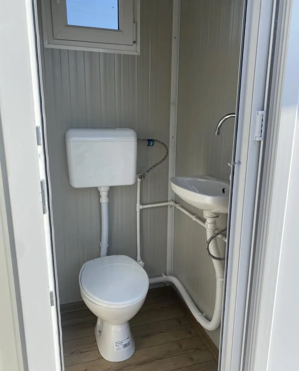 Inside a deluxe flushing portable toilet with a flush toilet and small sink