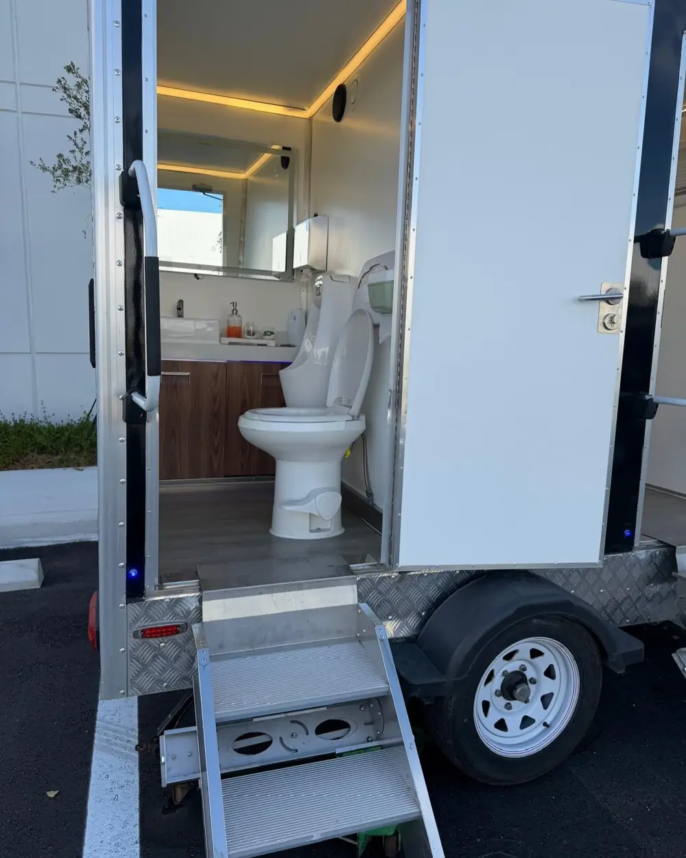 Restroom trailer with the door open and steps down to the ground