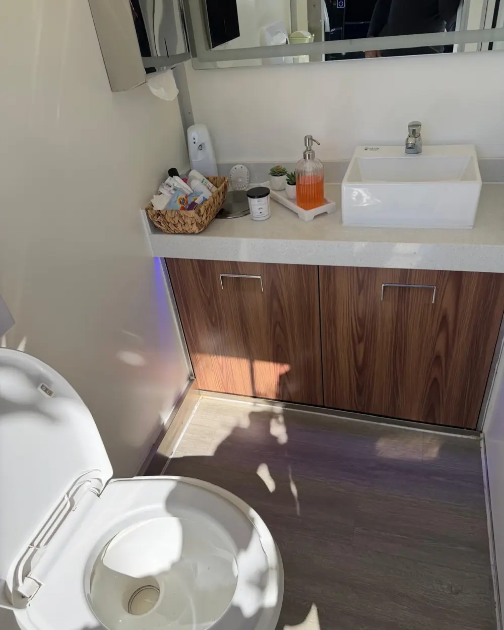 Restroom trailer interior with a wood vanity, vessel sink and toilet